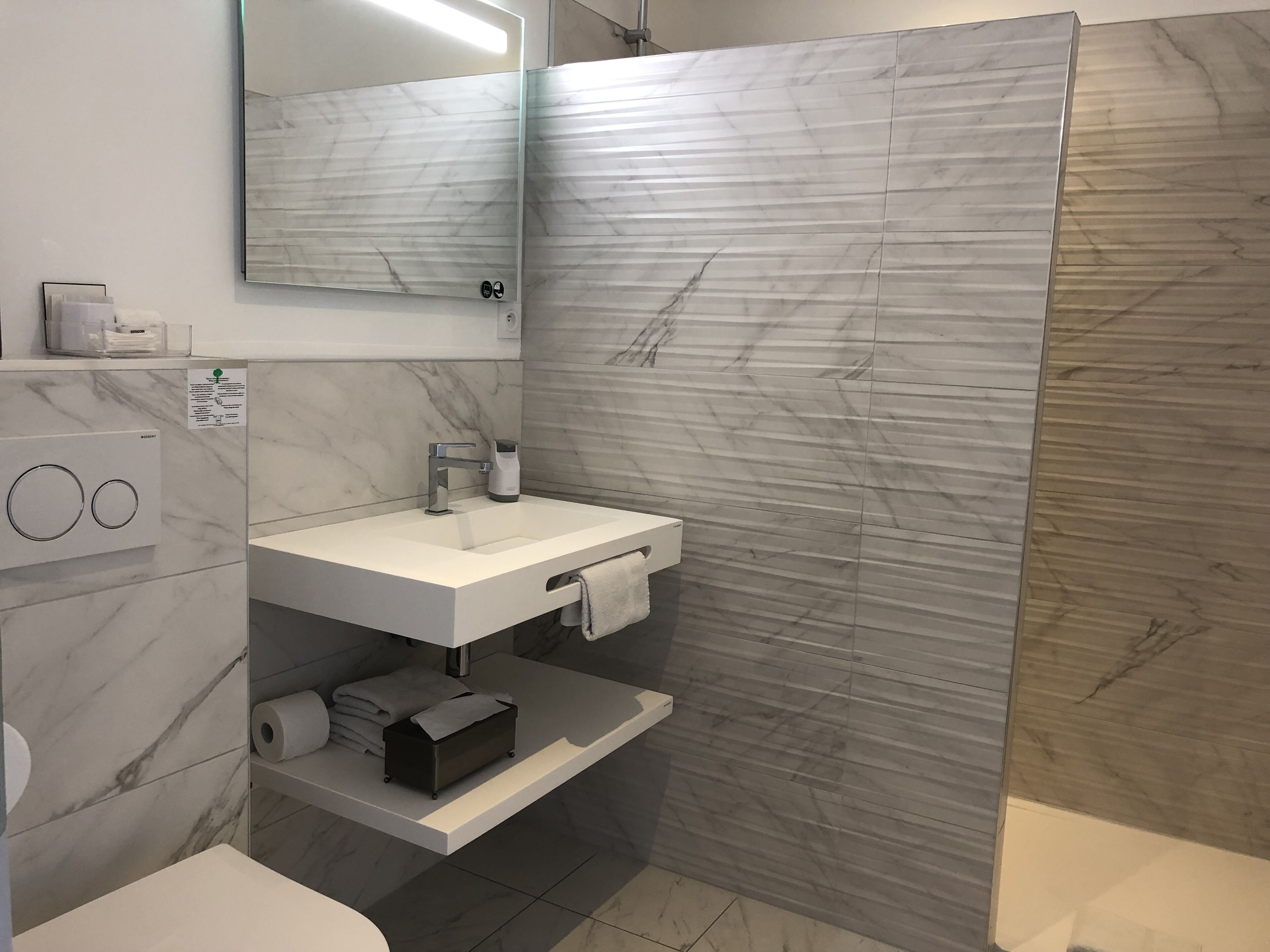Un baño moderno con tocador de mármol, cabina de ducha e inodoro empotrado.