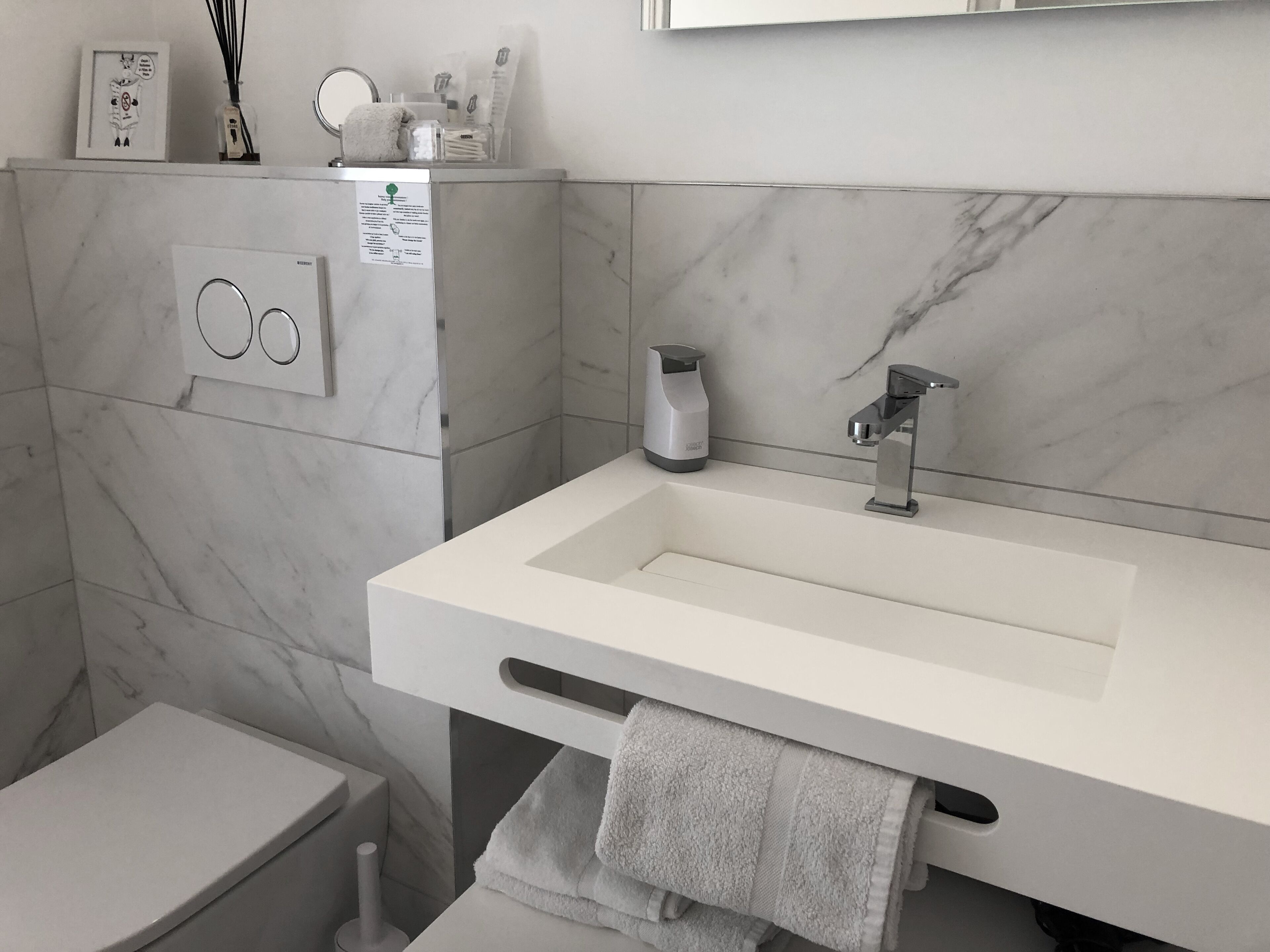 Un baño moderno con un lavamanos blanco, un perchero para toallas y un inodoro.