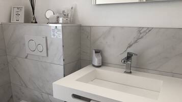 Un baño moderno con un lavamanos blanco, un perchero para toallas y un inodoro.