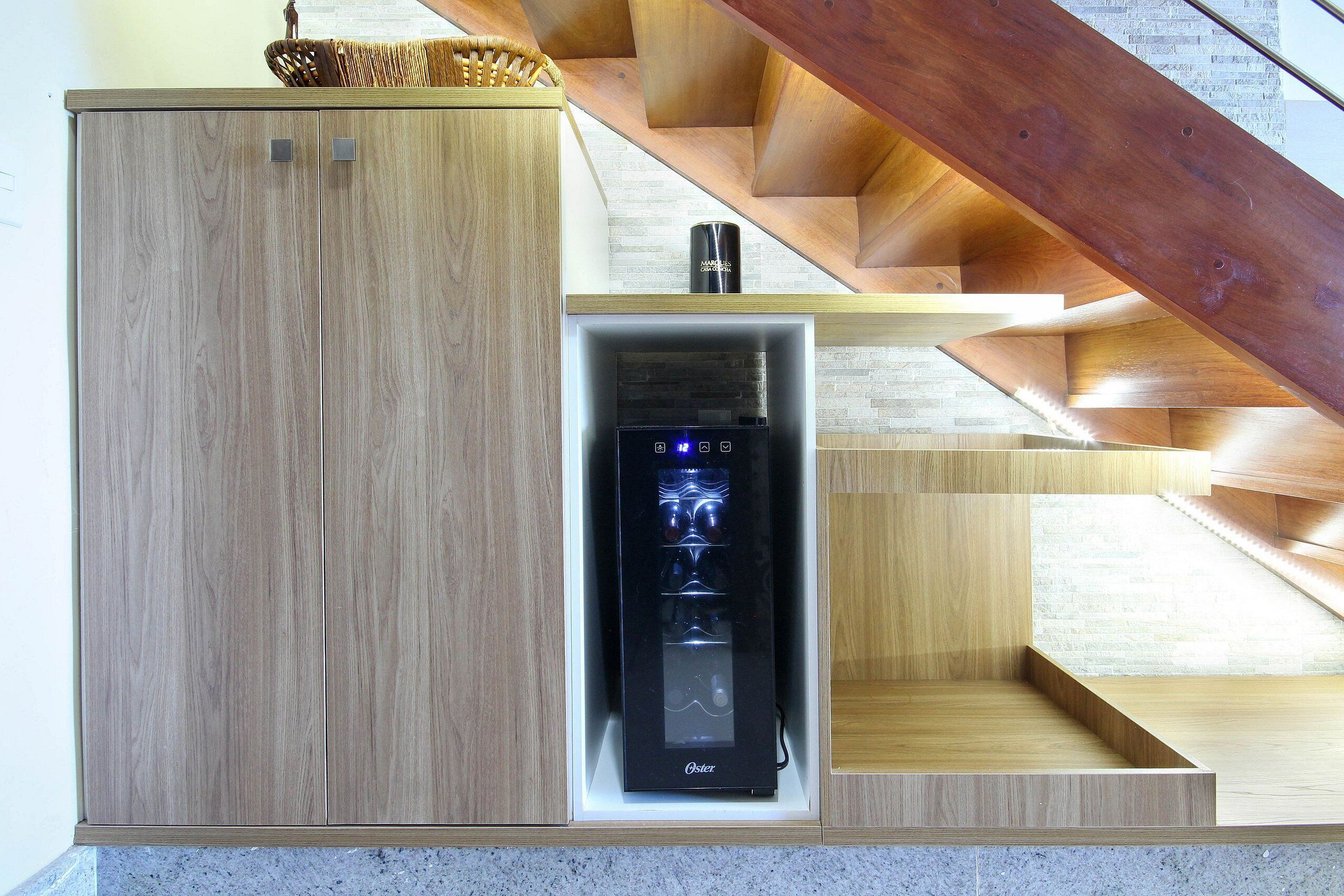 Une cuisine moderne dotée d’appareils électroménagers intégrés, de meubles de rangement en bois et d’un escalier avec une rampe en bois.