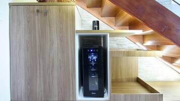 Une cuisine moderne dotée d’appareils électroménagers intégrés, de meubles de rangement en bois et d’un escalier avec une rampe en bois.