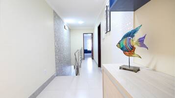 Un pasillo con piso de baldosas, barandilla de metal y una escultura decorativa de pez sobre un pedestal.