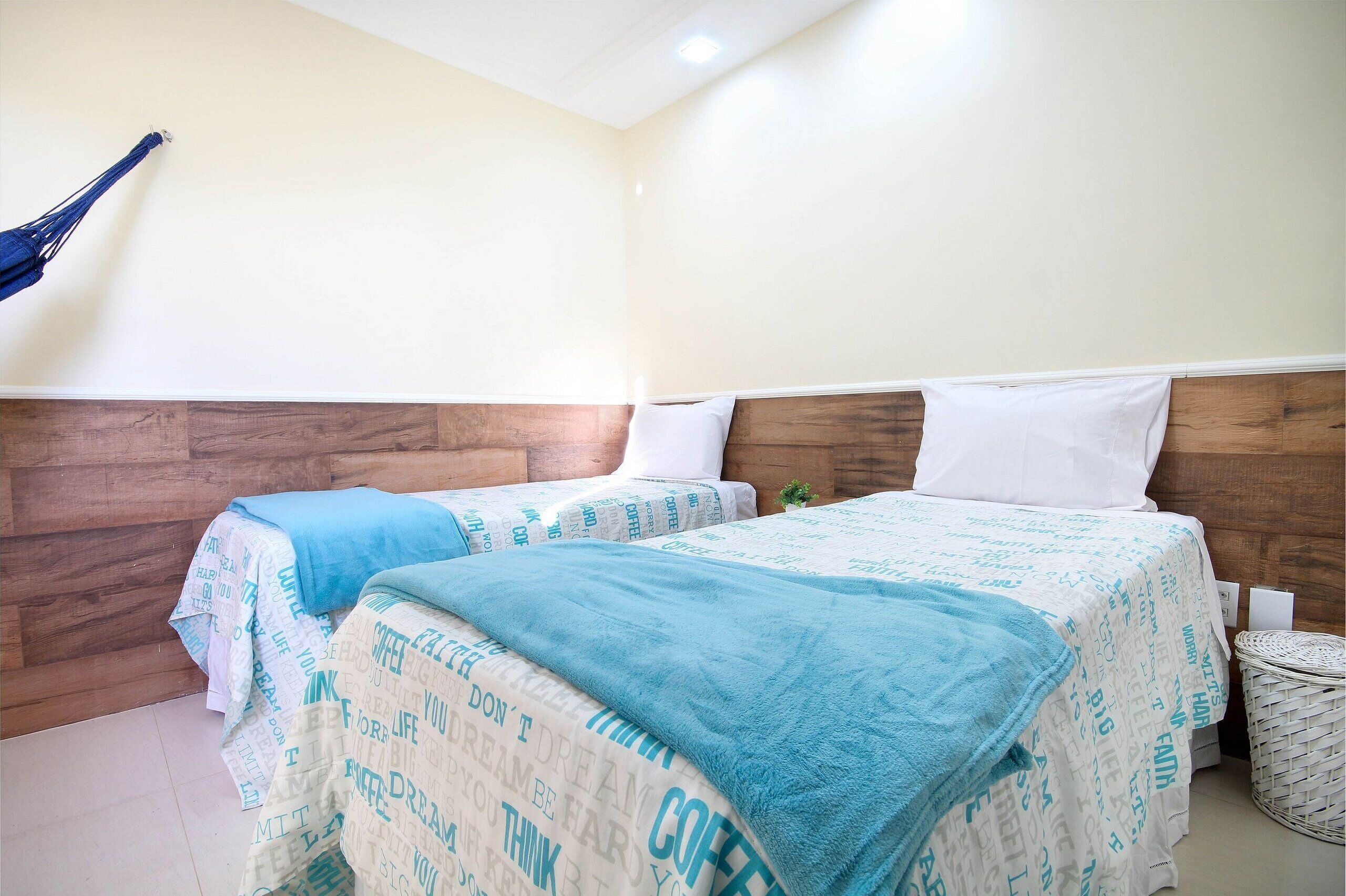 A hotel room with two beds, wooden headboards, and a small plant on the floor.