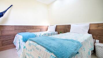 A hotel room with two beds, wooden headboards, and a small plant on the floor.