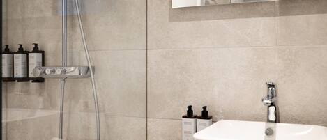 A modern bathroom with a shower, a sink, and toiletries on the counter.