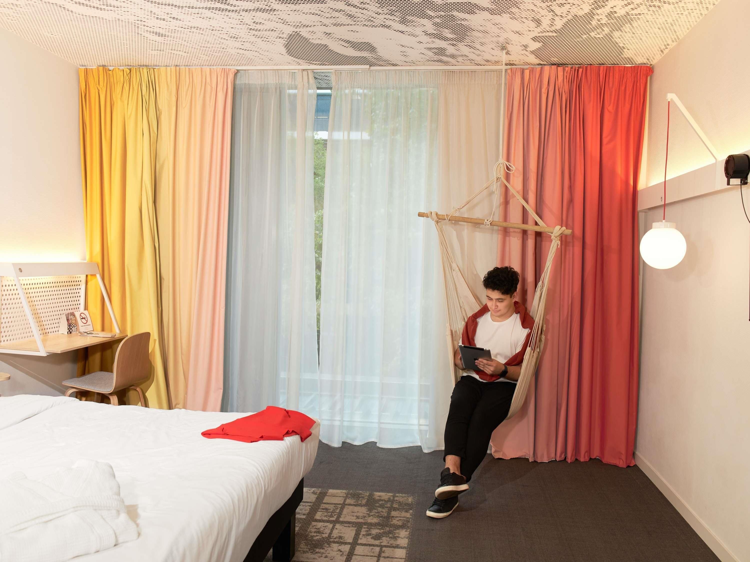 Una habitación con una cama, un escritorio y una silla colgante.