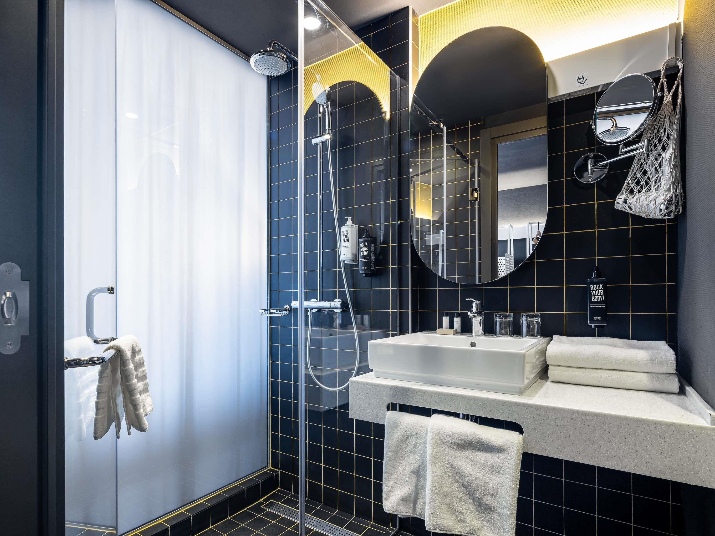 Une salle de bain moderne avec une douche à parois de verre, un meuble-lavabo avec deux vasques et un grand miroir.