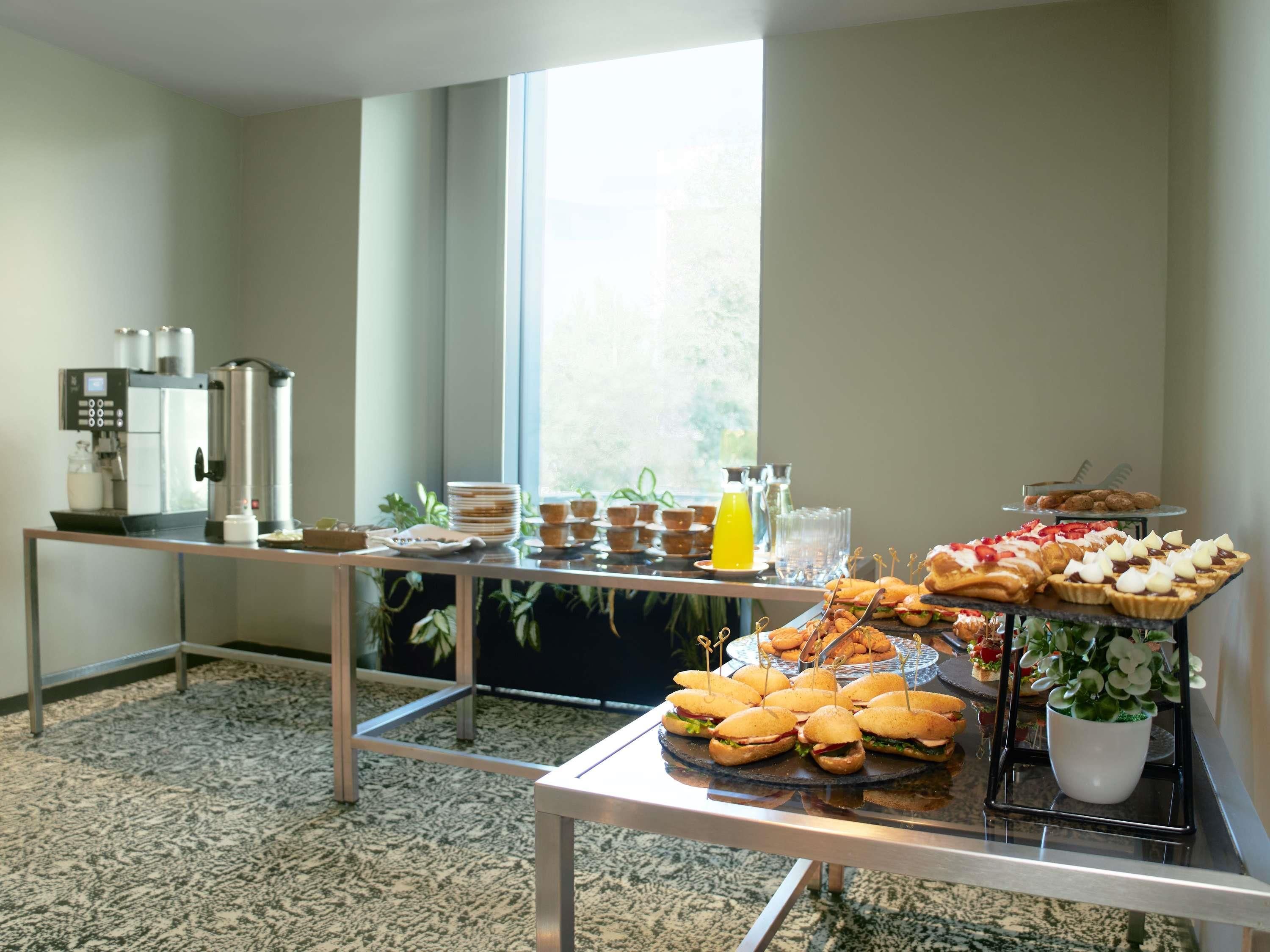 Un'attrezzatura per buffet con macchina del caffè, piatti, tazze e diversi tipi di cibo.