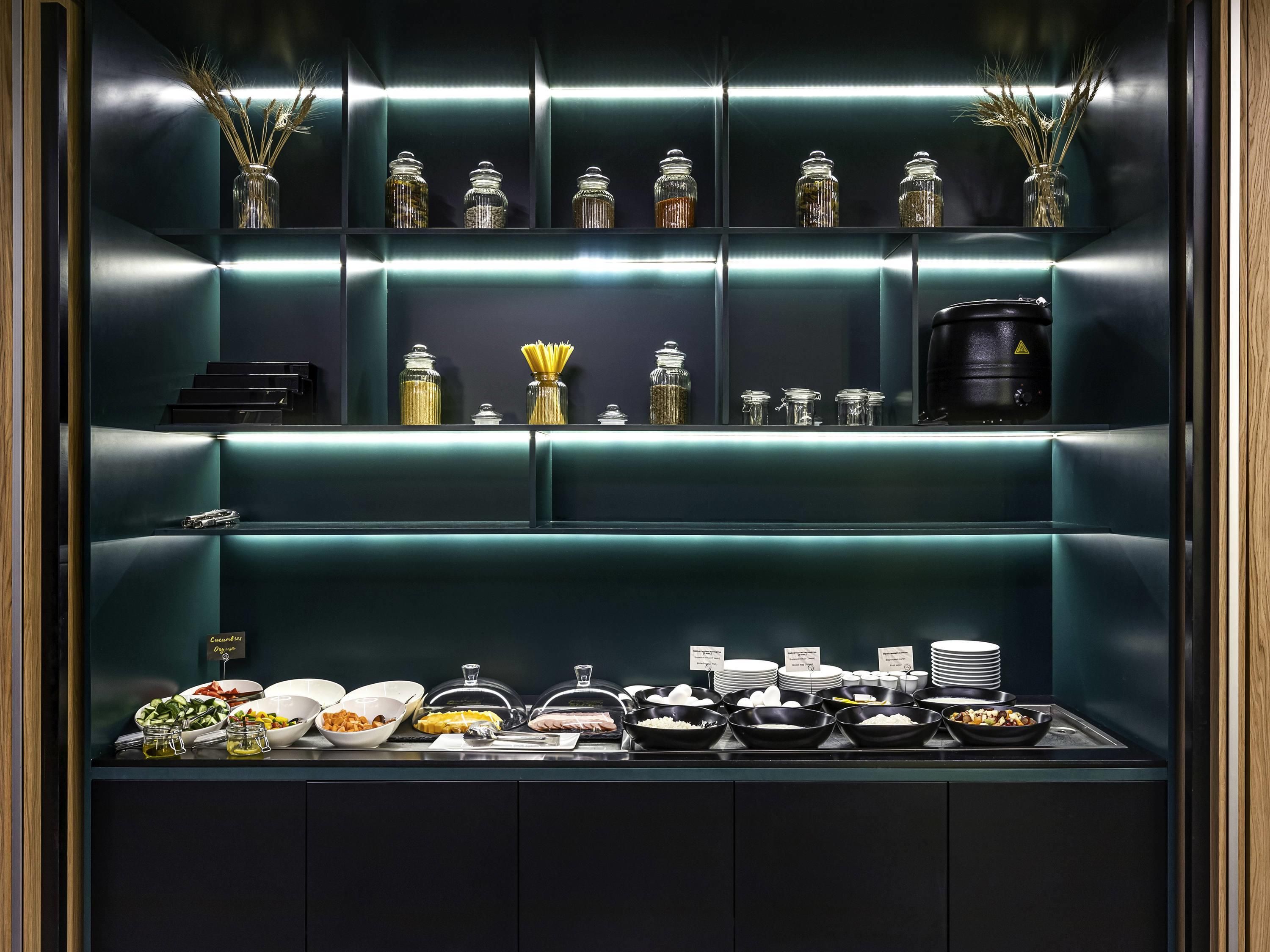 A buffet area with various food items and glass containers on shelves.