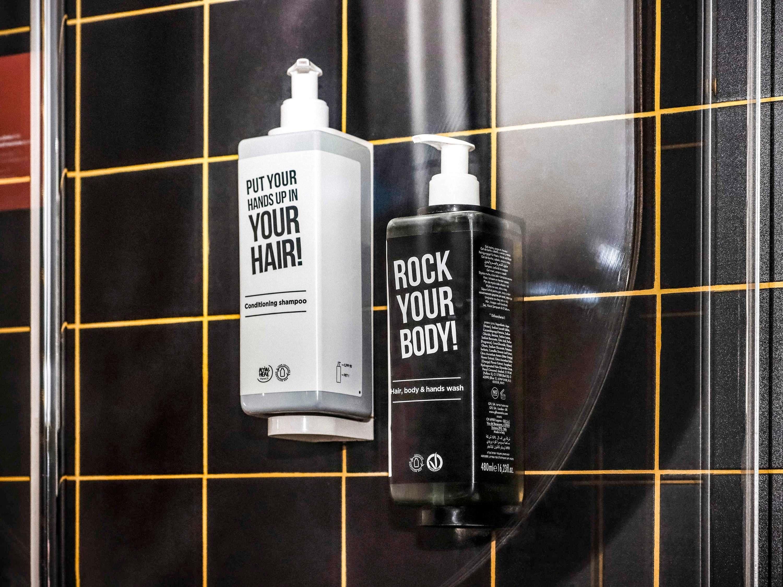 Zwei Shampoo-Flaschen an einer gefliesten Wand.