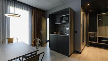 A modern kitchen with dark cabinetry, a built-in oven, and a dining area with a wooden table and chairs.