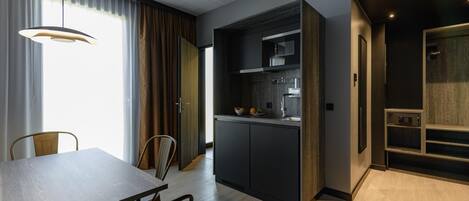 A modern kitchen with dark cabinetry, a built-in oven, and a dining area with a wooden table and chairs.