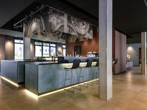 Een moderne bar met een toog, zitplaatsen en een grote decoratieve wand.