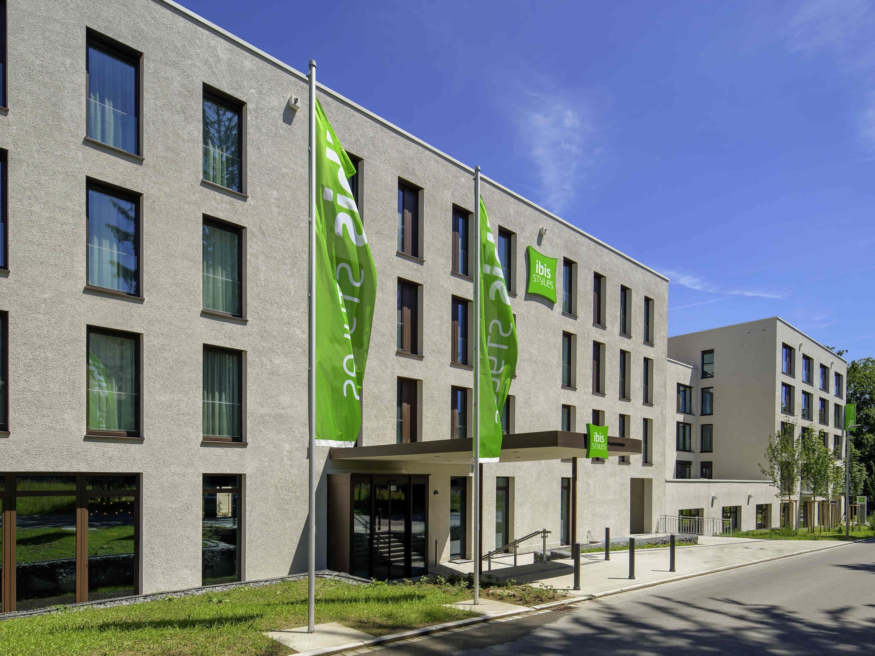 Ein modernes Gebäude mit vielen Fenstern und grünen Flaggen.