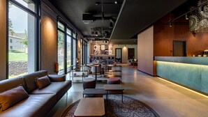 Eine geräumige Lobby mit modernem Design, inklusive einer Ledersofa, einem Couchtisch und einem gemusterten Teppich.