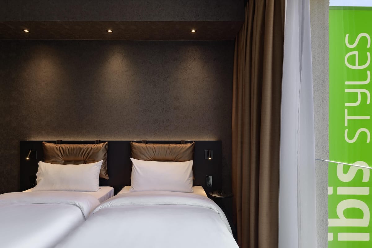 Une chambre d’hôtel dotée d’un grand lit, d’une tête de lit avec éclairage intégré et offrant une vue sur l’extérieur.