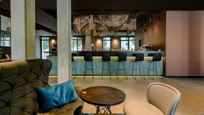 Een moderne lounge met een bar, zitplaatsen en een decoratief plafondschilderij.