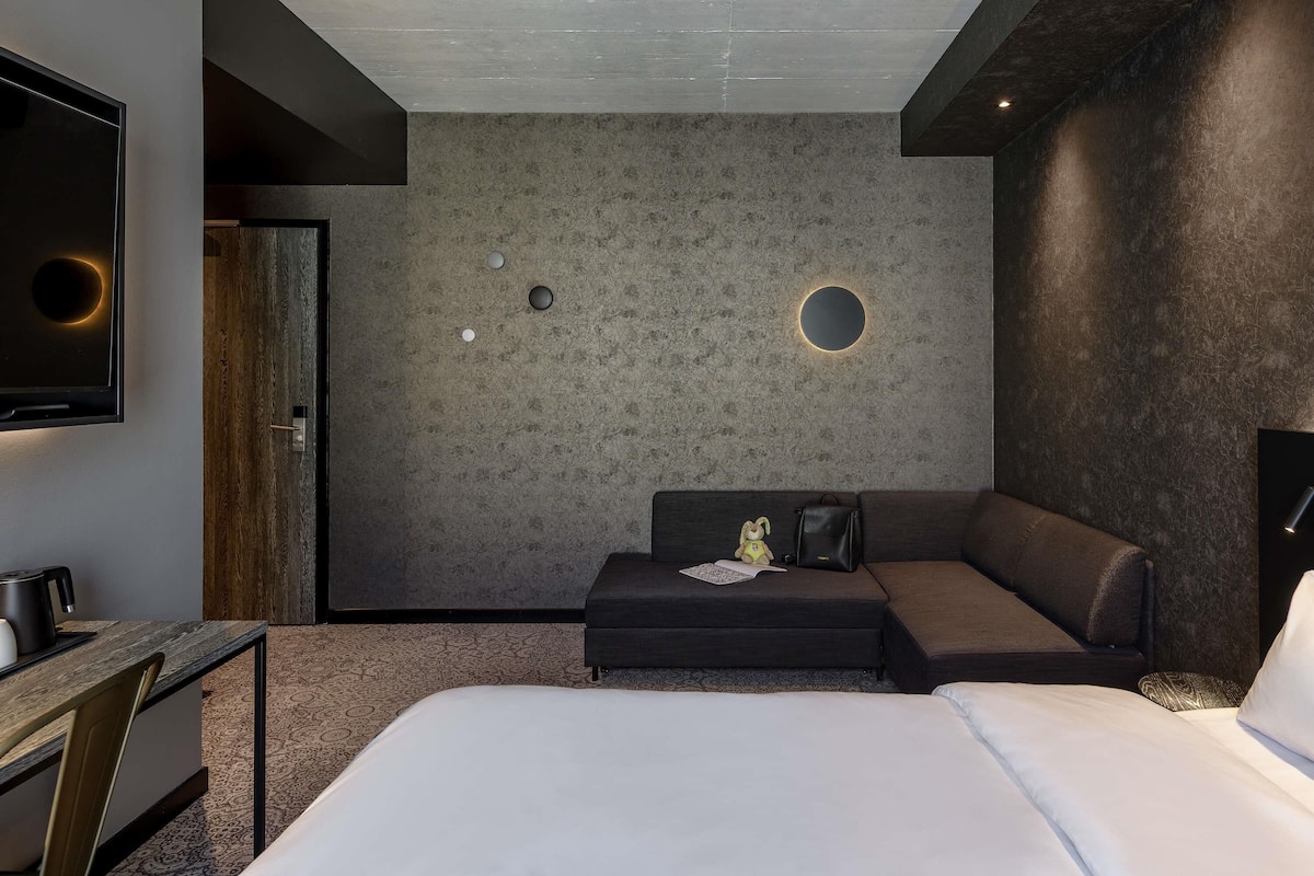 Une chambre d’hôtel moderne, dotée d’un grand lit, d’un bureau et d’un coin salon.