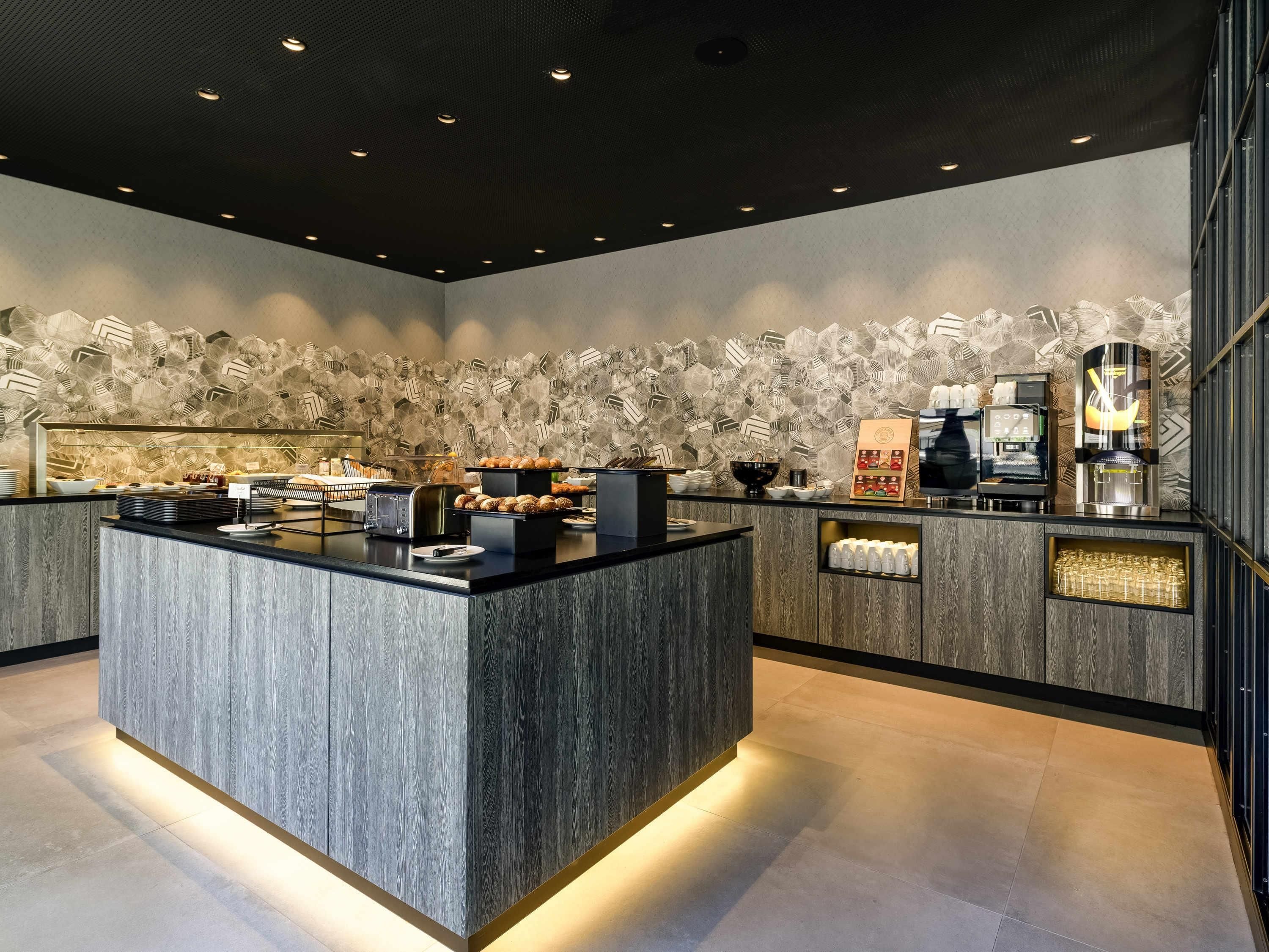 A modern kitchen with a central island, a coffee machine, and a patterned wall.