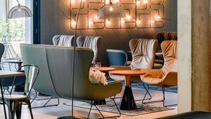 Ein modernes Interieur mit einer Sitzecke, ausgestattet mit einer Couch und Sesseln, einem Tisch und einer Wandleuchte.