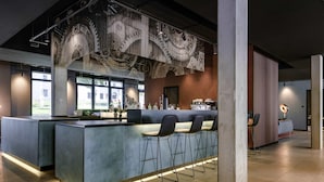 Eine moderne Bar mit einer Theke, Sitzgelegenheiten und einer großen Wandverkleidung.