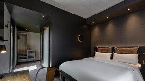 Een moderne hotelkamer met een groot bed, een eettafel en een aparte zithoek.