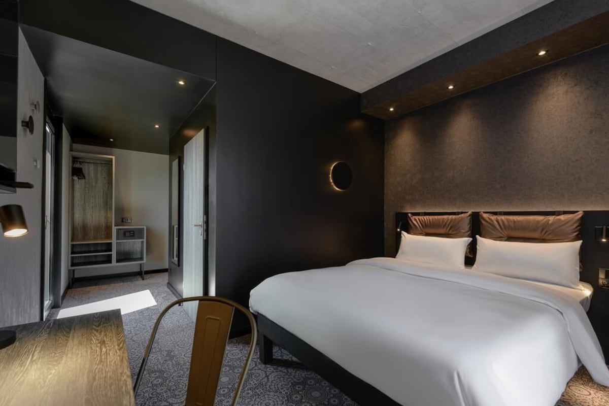 Une chambre d’hôtel moderne dotée d’un grand lit, d’une table à manger et d’un coin salon séparé.