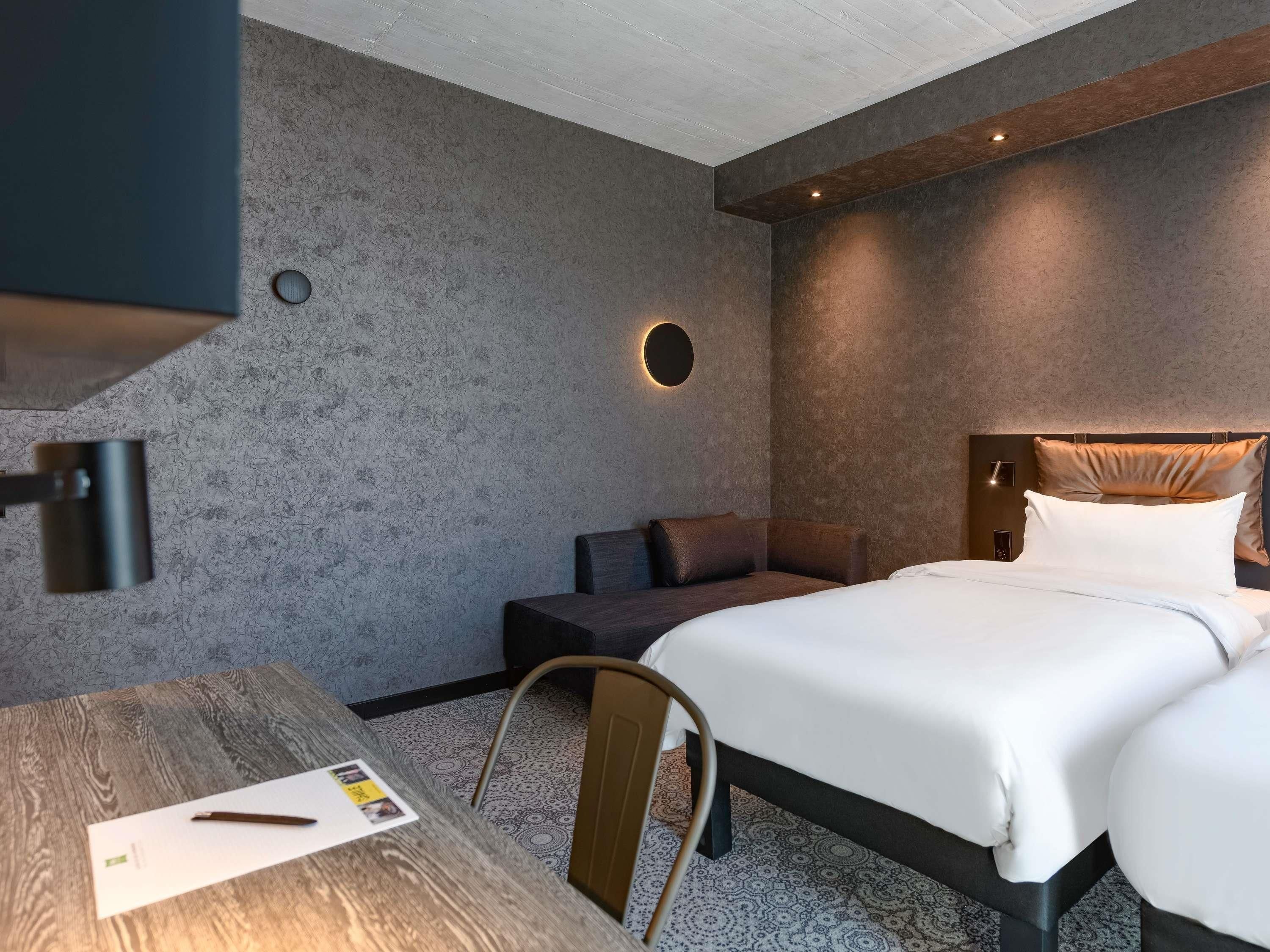 Una habitación de hotel moderna con una cama grande, un escritorio y una silla.
