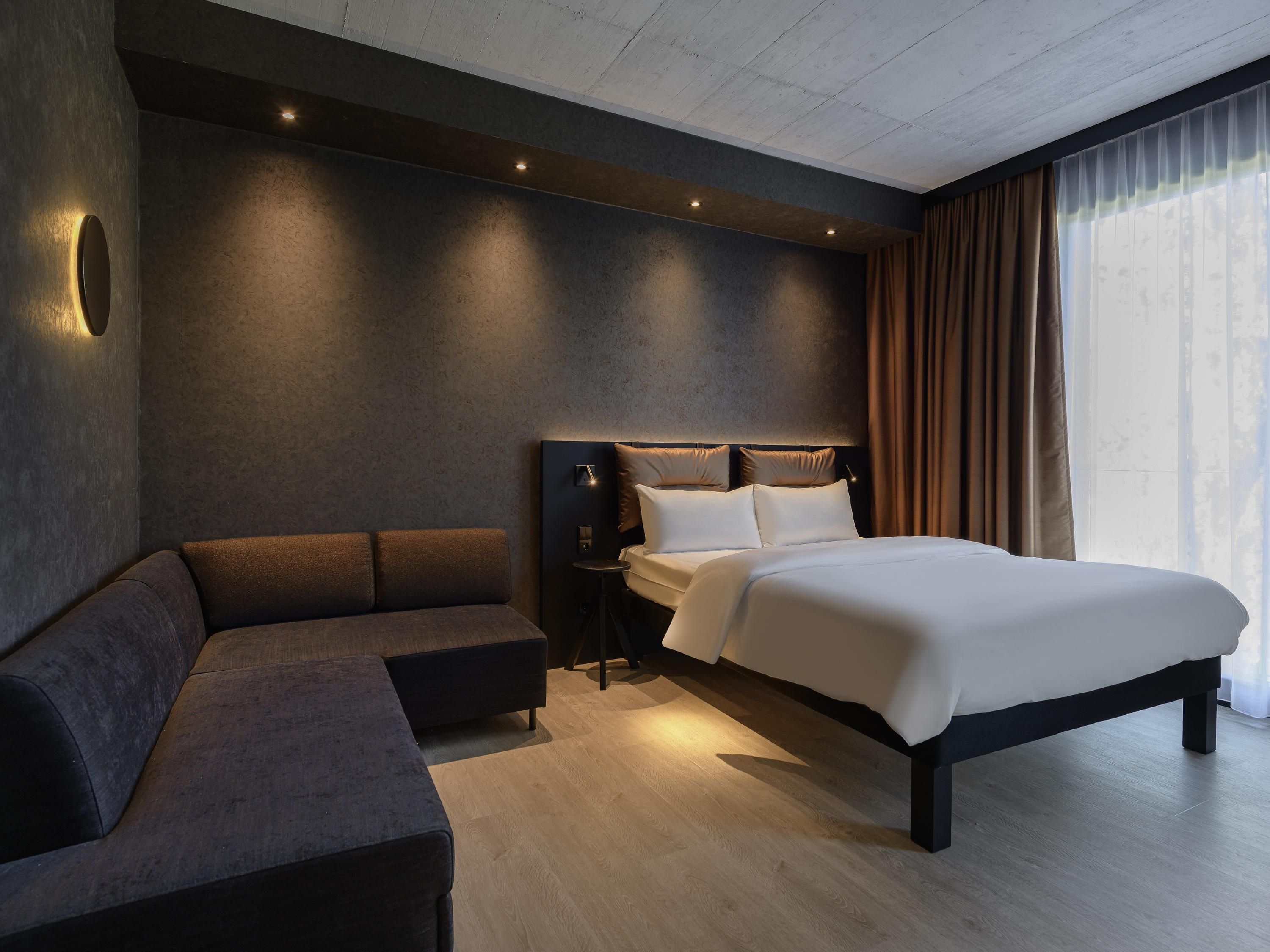 Une chambre d’hôtel moderne avec un grand lit, un canapé et une table de chevet.