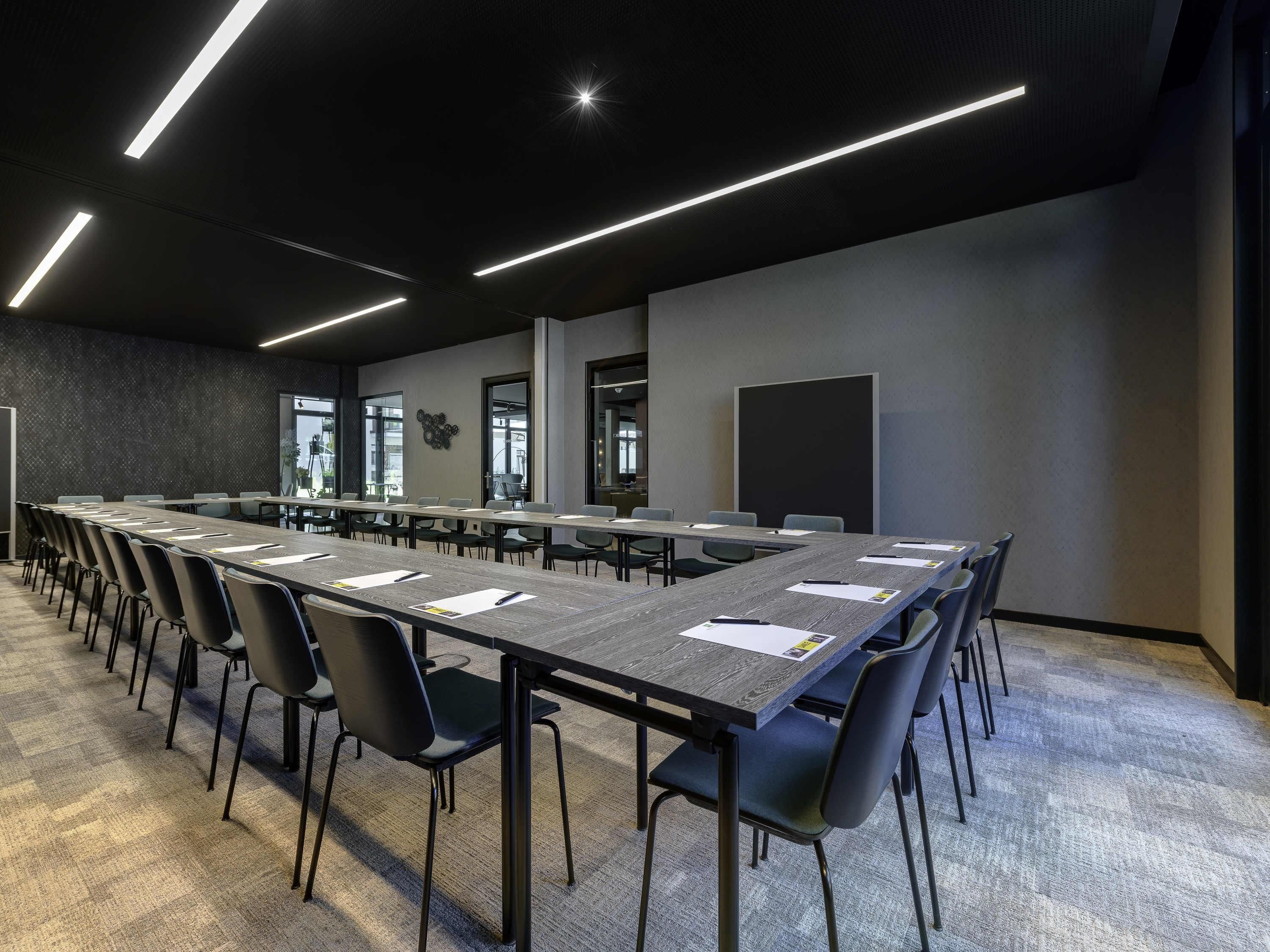 A conference room with a long table, chairs, a whiteboard, and a projector screen.
