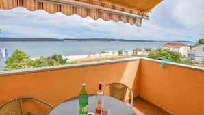 A balcony with a table, chairs, a bottle of wine, and a glass of wine. - Apartments Taya (Dobropoljana)