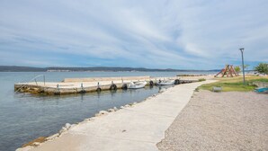 A waterfront pier with boats docked, a playground, and a clear view of the water and distant land. - Apartments Taya (Dobropoljana)