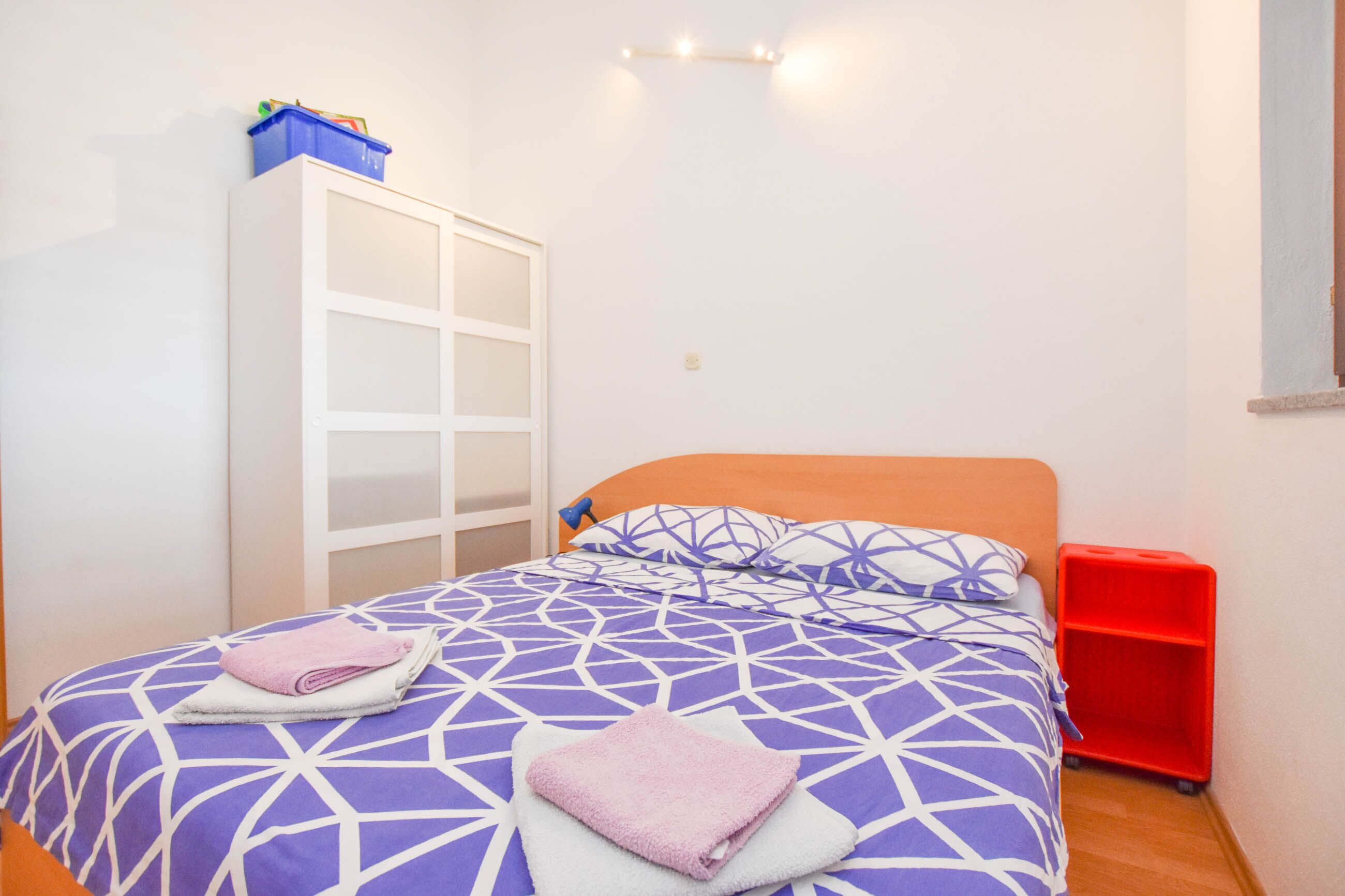 Une chambre à coucher avec un lit, une armoire et un meuble de rangement rouge.