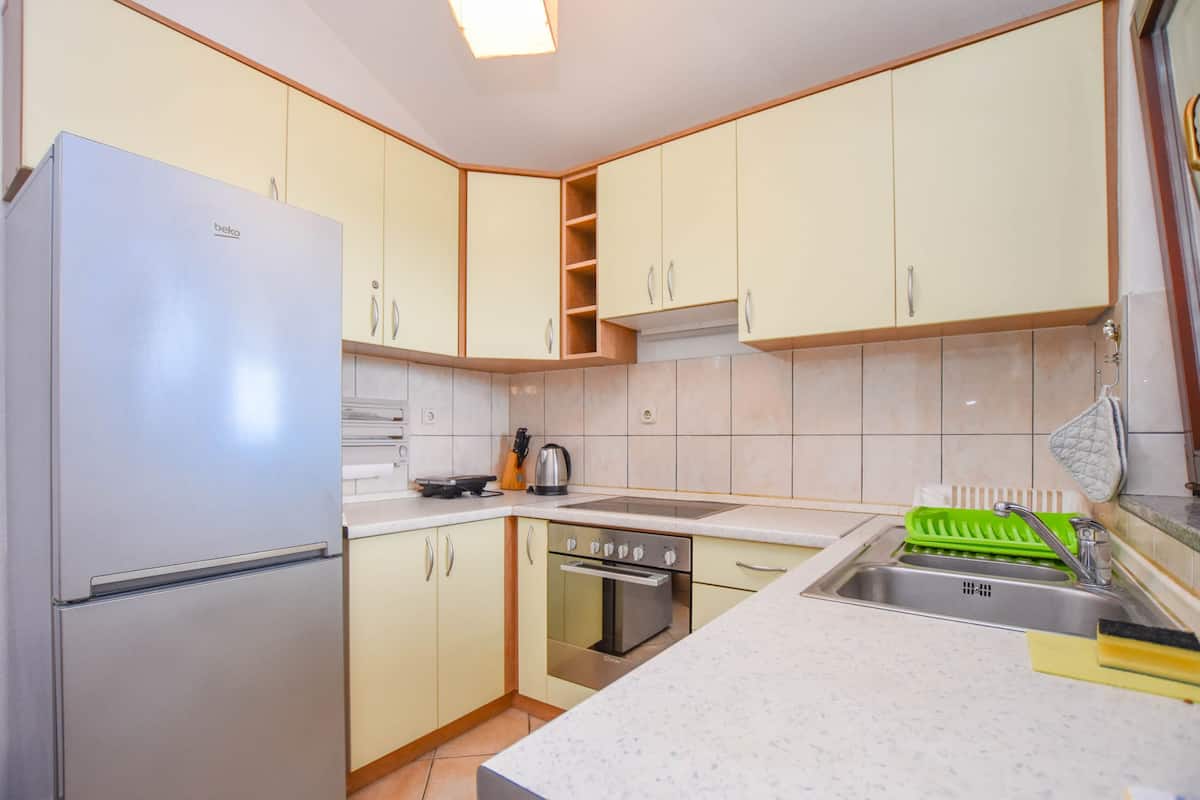 A kitchen with a refrigerator, stove, sink, and cabinets.