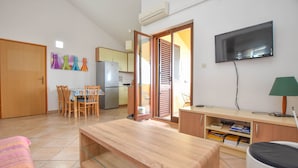 A compact living space with a dining area, kitchenette, and a TV mounted on the wall. - Apartments Taya (Dobropoljana)