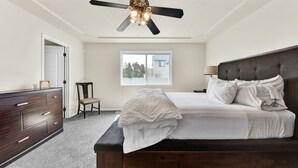 A bedroom with a dark wood bed, white bedding, a ceiling fan, a window, and a dresser. - Spacious Cozy Home by Settlers Park --  Meridian, ID (Meridian)