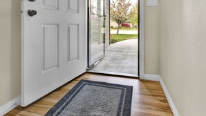 A hallway with a white door, a glass door leading outside, and a dark rug on the floor. - Spacious Cozy Home by Settlers Park --  Meridian, ID (Meridian)