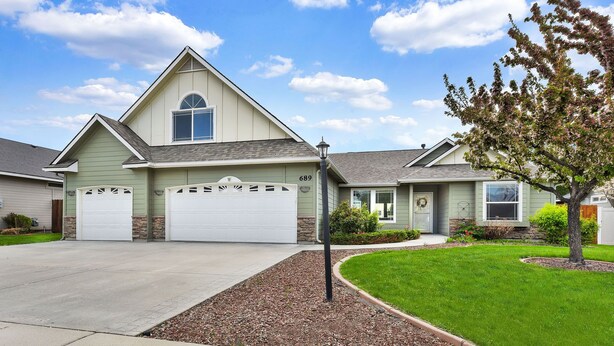 A single-story house with a garage, a front yard with a tree, and a clear sky. - Spacious Cozy Home by Settlers Park --  Meridian, ID (Meridian)