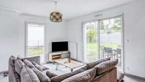 Een moderne woonkamer met een bank, salontafel, televisie en een hanglamp.