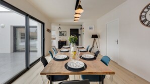 A modern dining area with a long wooden table set for six, surrounded by chairs. - La Roskoker - Villa 4 chambres et piscine privée proche plage - Roscoff (Roscoff)