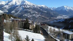 A mountainous landscape with snow-covered peaks and a valley with buildings. - T3 PRA LOUP 56 M2 Magnificent valley and mountain views 2 bedrooms (Uvernet-Fours)