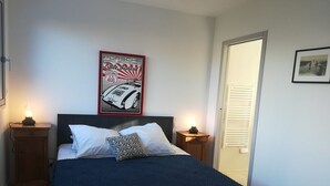 A bedroom with a bed, two bedside tables, a wall-mounted poster, and a door. - UNIQUE VIEW TOUR DE LA LANTERNE Apartment WITH TERRACE 2-4 PERS. (La Rochelle)