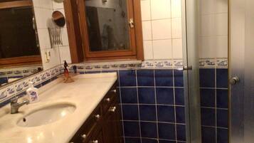 A bathroom with a sink, mirror, and shower.