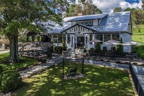 A two-story house with a covered patio area featuring outdoor seating and umbrellas. - Outdoor Fireplace, S'mores & Mountain Air⎮Game Room⎮Dog Friendly Sleeps 10 (Mineral Bluff)