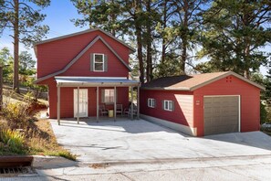 Une maison rouge à deux étages, avec un garage, une véranda et une allée.