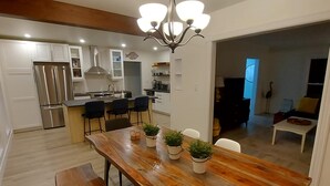 Una cucina moderna con forno a incasso, frigorifero in acciaio inossidabile e zona pranzo con tavolo e panche in legno.