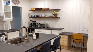 Una cucina moderna con isola centrale, sgabelli da bar, macchina del caffè e forno integrato.