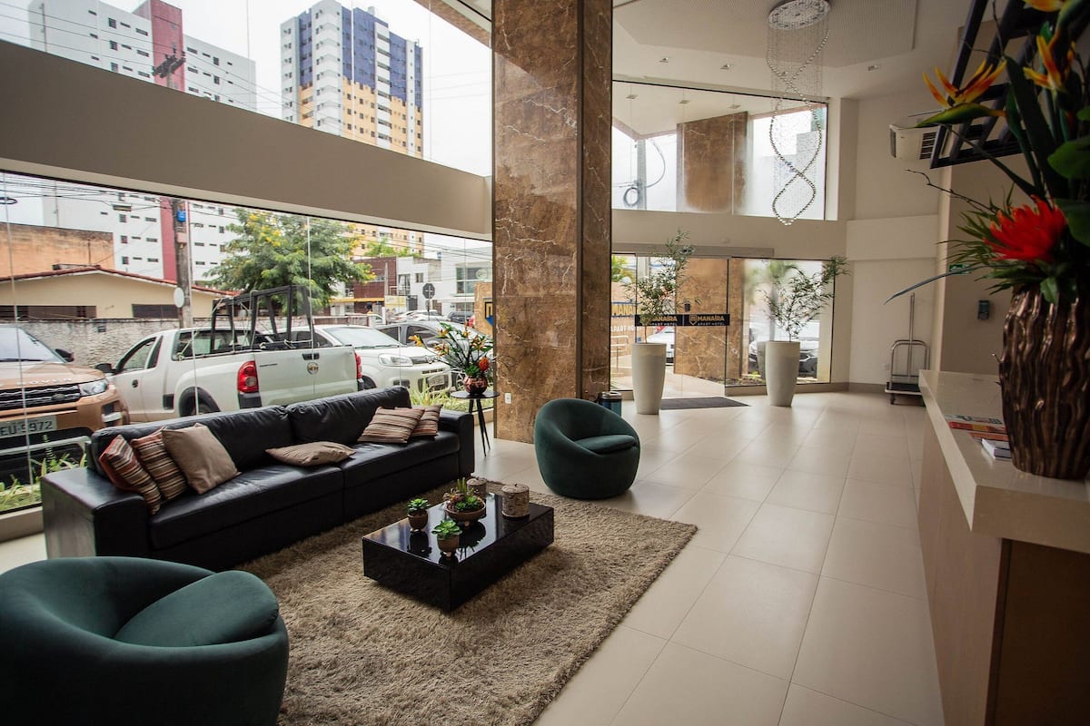 A spacious lobby with a black leather sofa, a glass coffee table, and a large pillar.