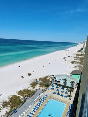 A beach resort with a swimming pool, beach chairs, and a view of the ocean. - Gorgeous Beachfront Condo! (Panama City Beach)