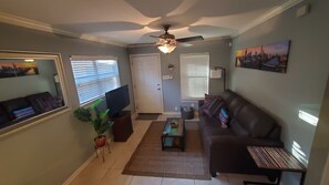 A living room with a sofa, a coffee table, a TV, and a ceiling fan.
